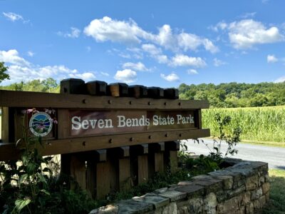 Entrance sign for Seven Bends State Park in Woodstock, Virginia, on a bright spring day with clear blue skies.