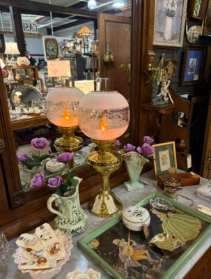 Antique brass lamps and vintage collectibles displayed on a marble-top vanity.